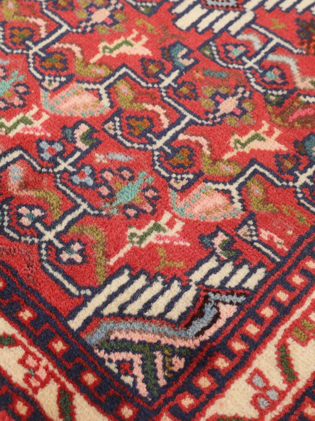Hand-knotted Asadabad rug from the Middle East with a vibrant red field and geometric patterns
