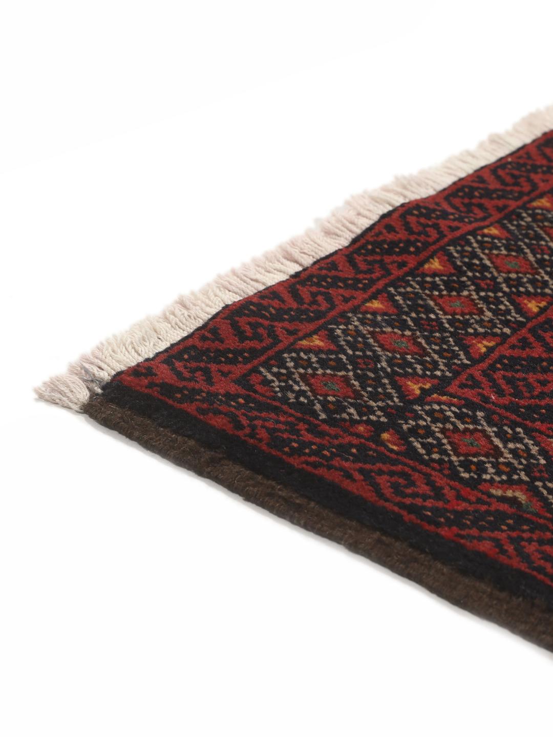 Hand-knotted Baluch rug from the Middle East in deep red and black tones
