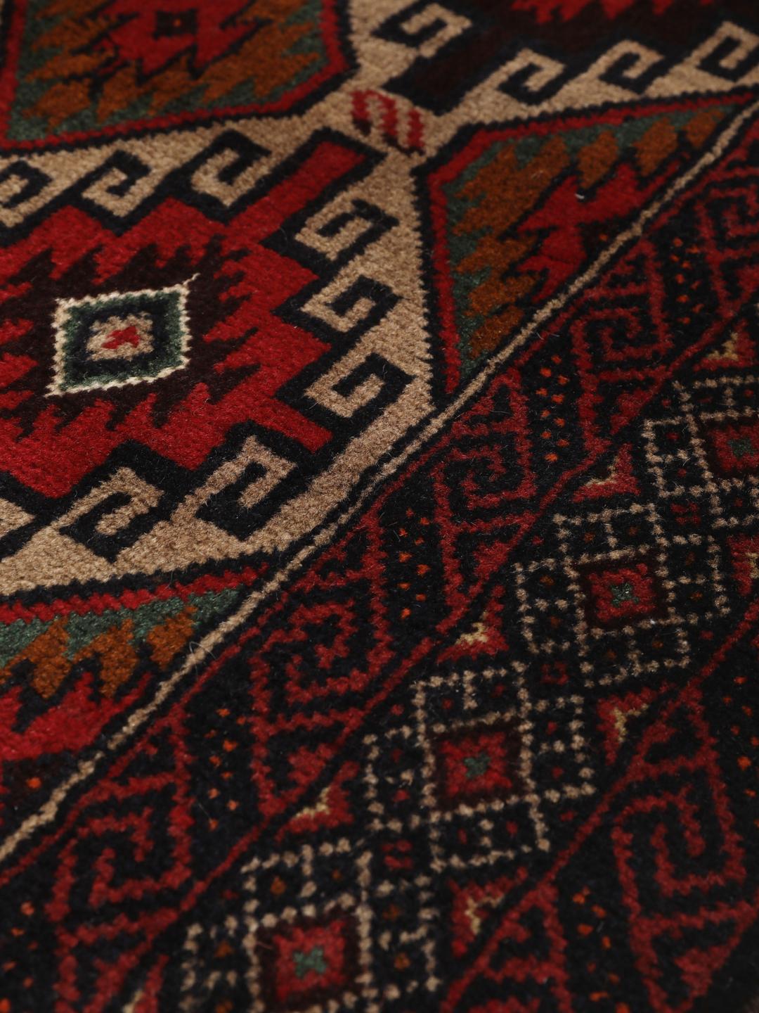 Hand-knotted Baluch rug from the Middle East in deep red and black tones