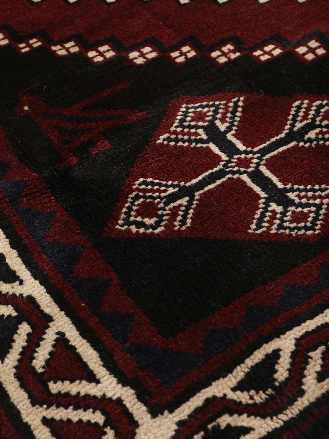 A hand-knotted Lori rug from the Middle East featuring a dark-red and black geometric pattern.