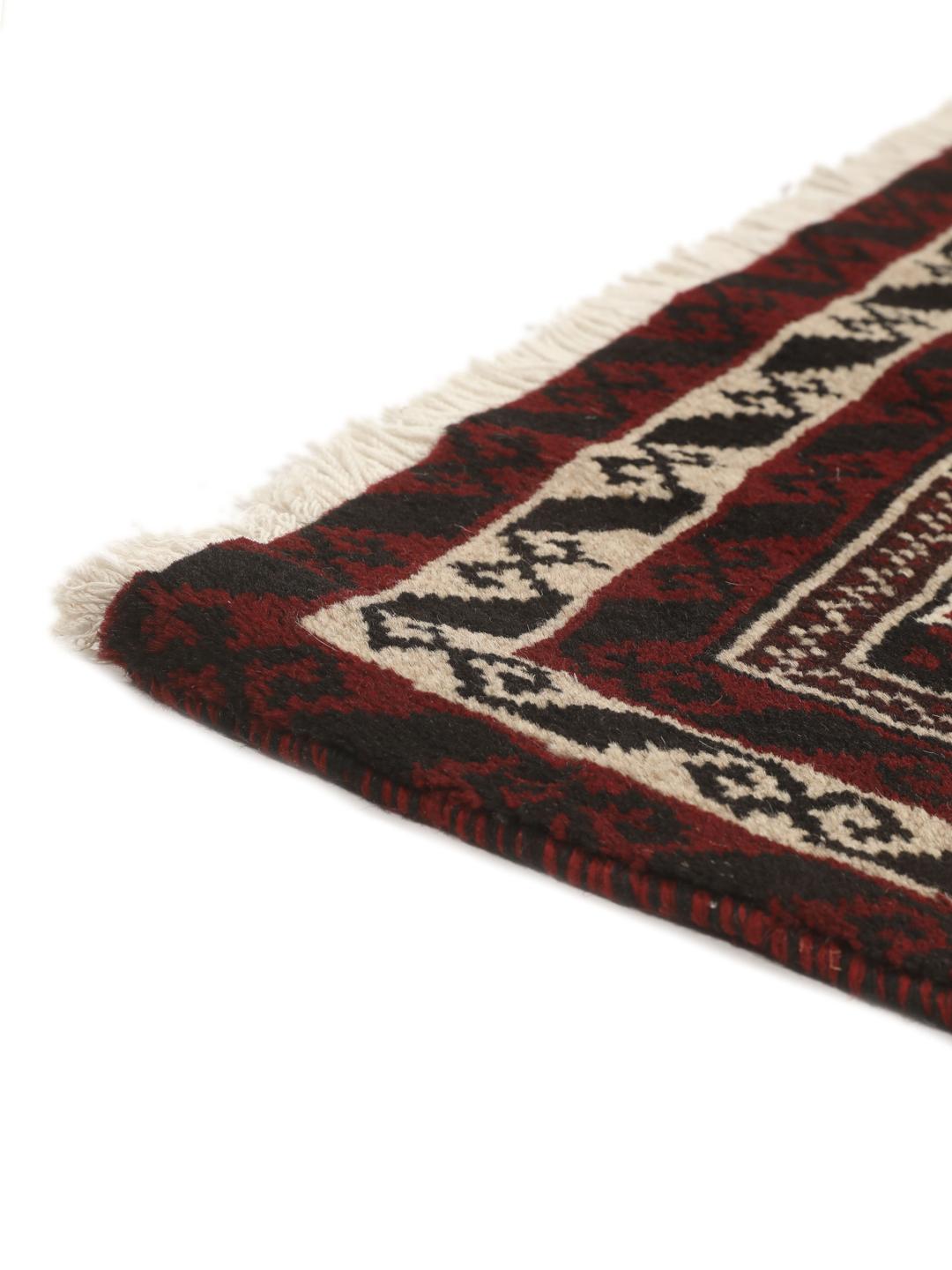 Et håndknyttet Baluch-tæppe fra Mellemøsten med et mørkerødt og beige tribal-design