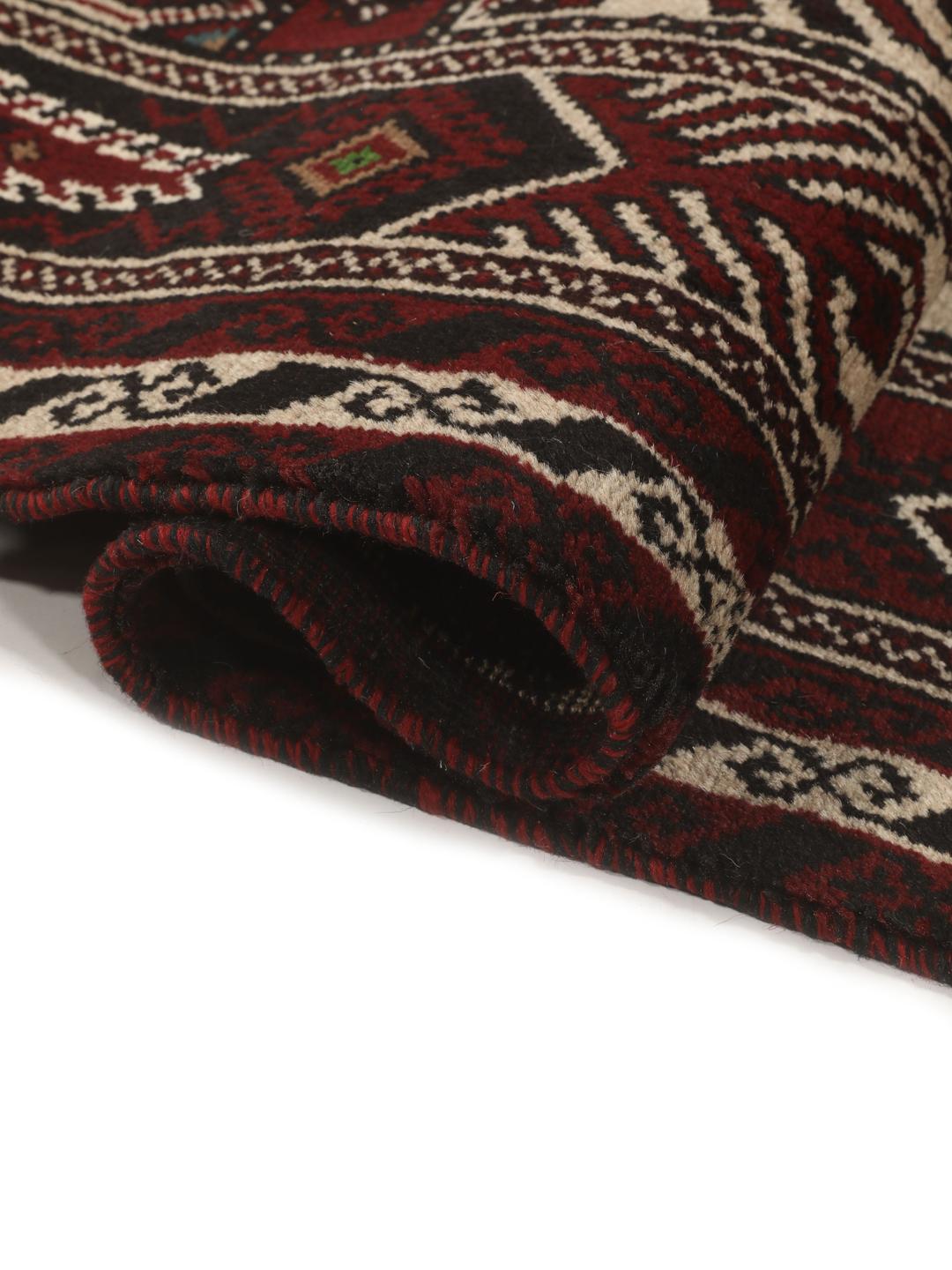Et håndknyttet Baluch-tæppe fra Mellemøsten med et mørkerødt og beige tribal-design