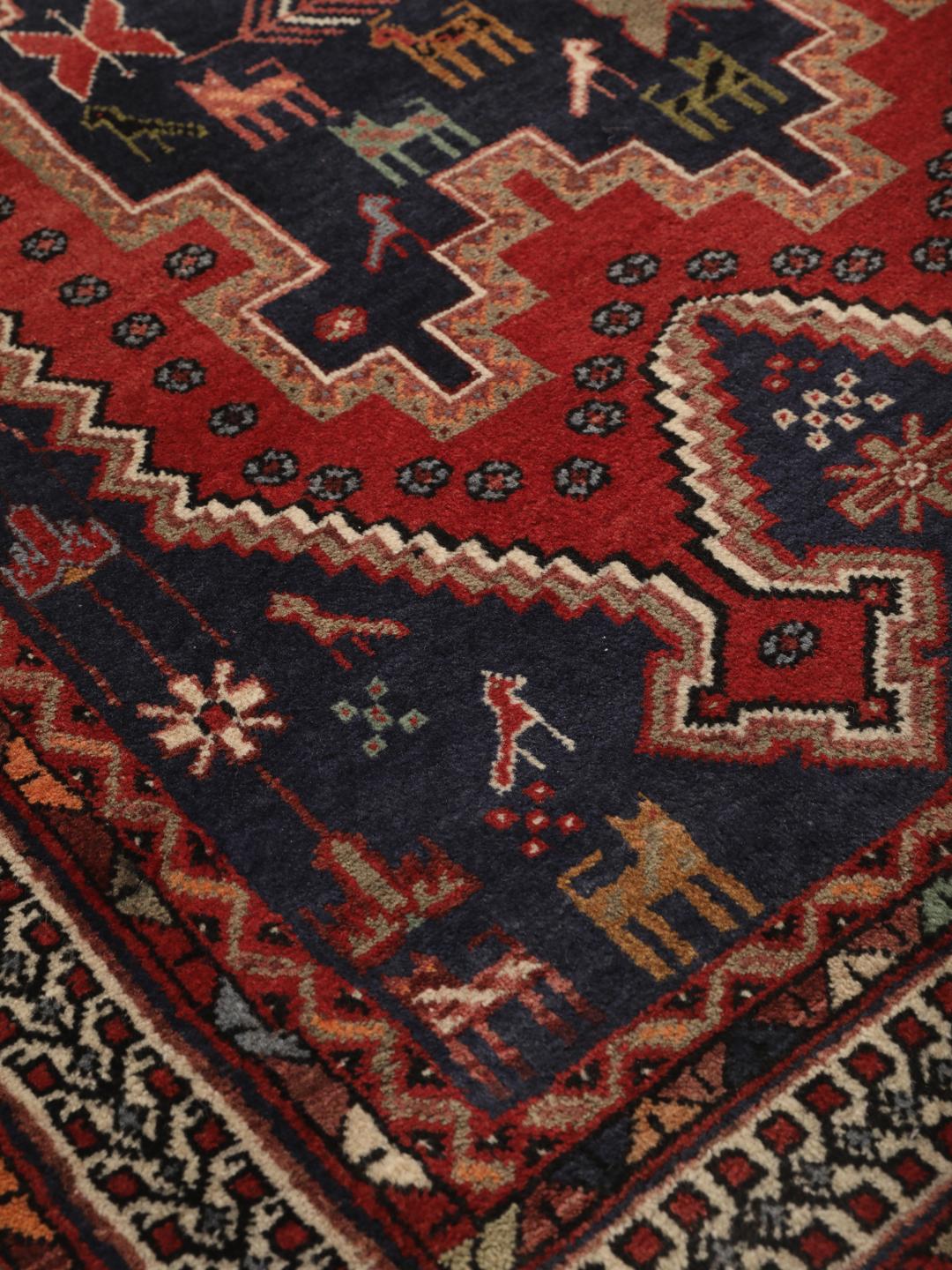 Hand-knotted Afshar rug from the Middle East featuring a red and blue field with tribal animal motifs.