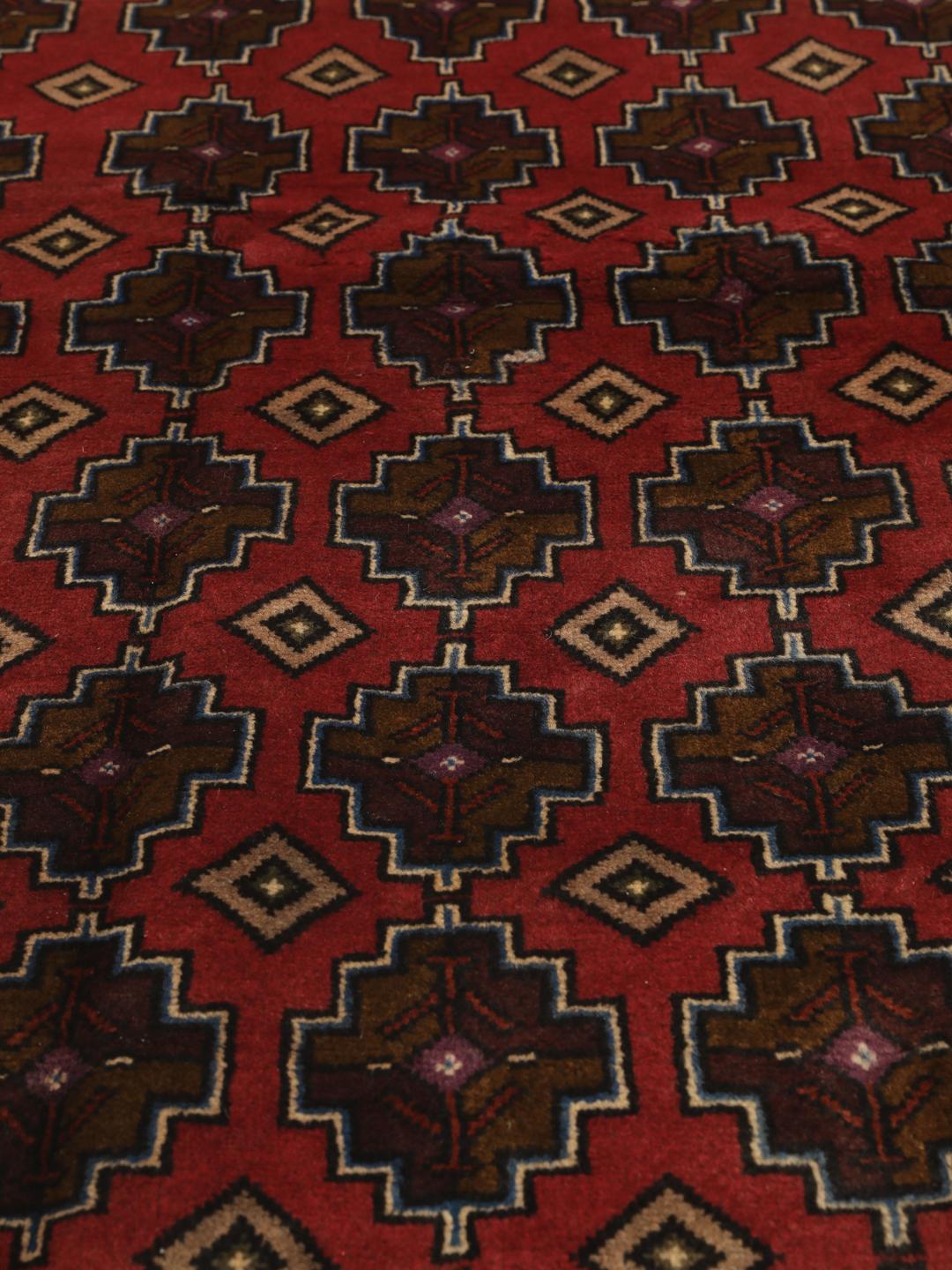 Hand knotted Baluch rug from the Middle East in dark-red with geometric motifs