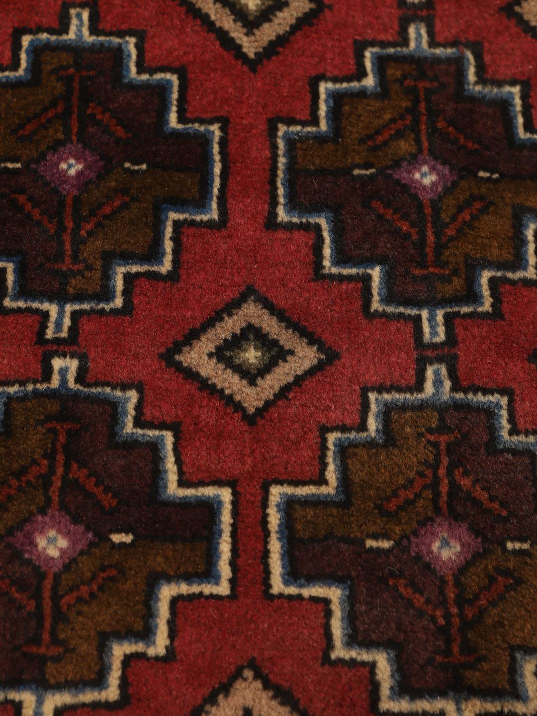 Hand knotted Baluch rug from the Middle East in dark-red with geometric motifs