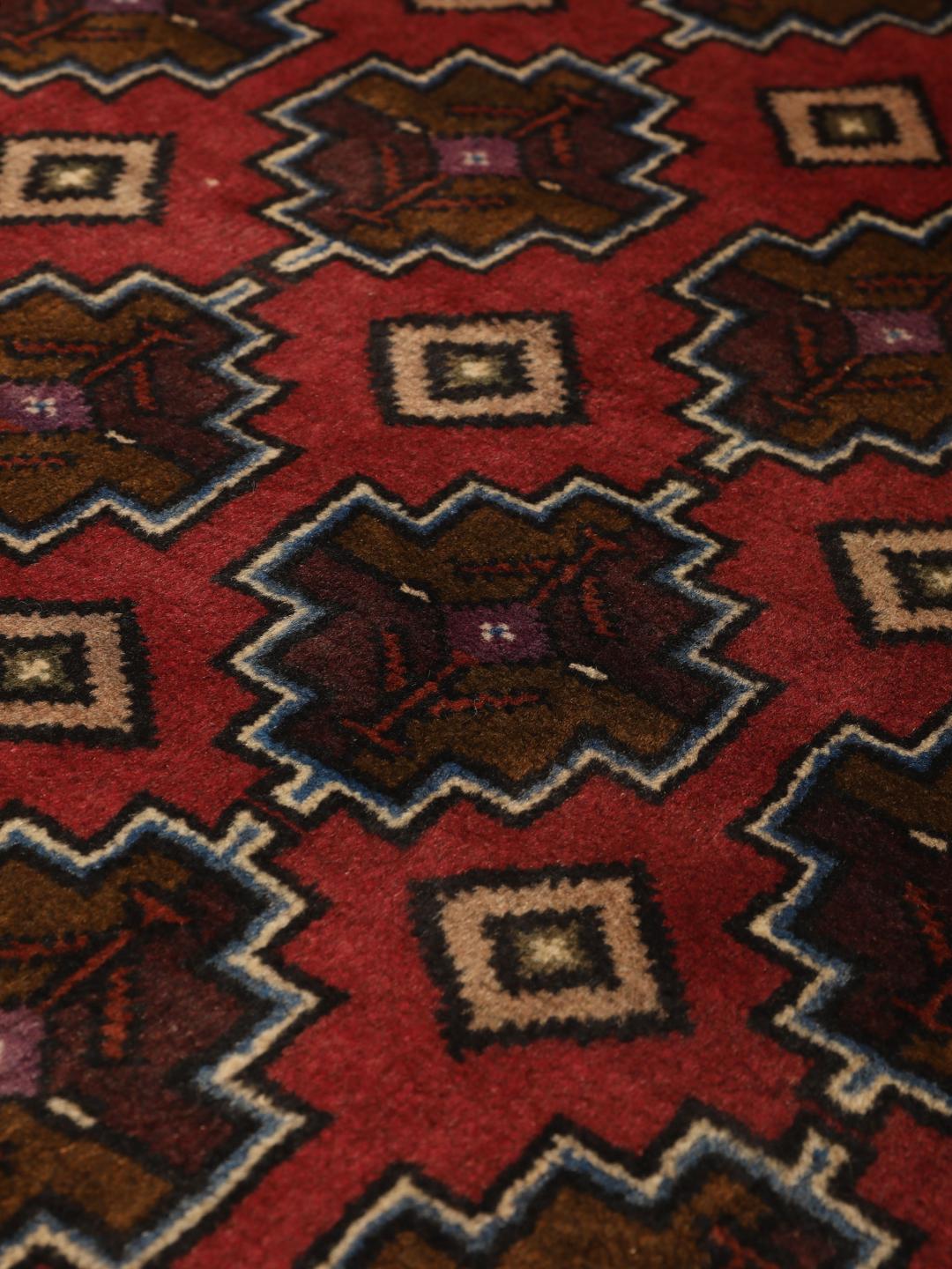 Hand knotted Baluch rug from the Middle East in dark-red with geometric motifs