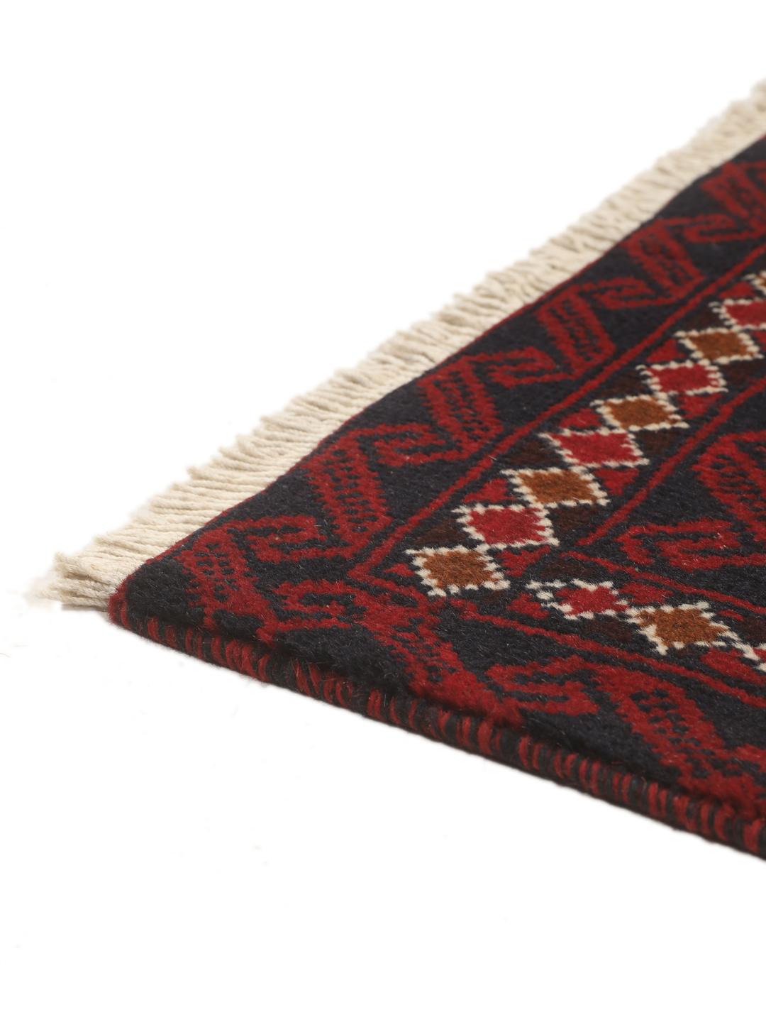 Handgeknoopt Beluch-tapijt uit het Midden-Oosten in donkerrode en donkerblauwe tinten met geometrische motieven.