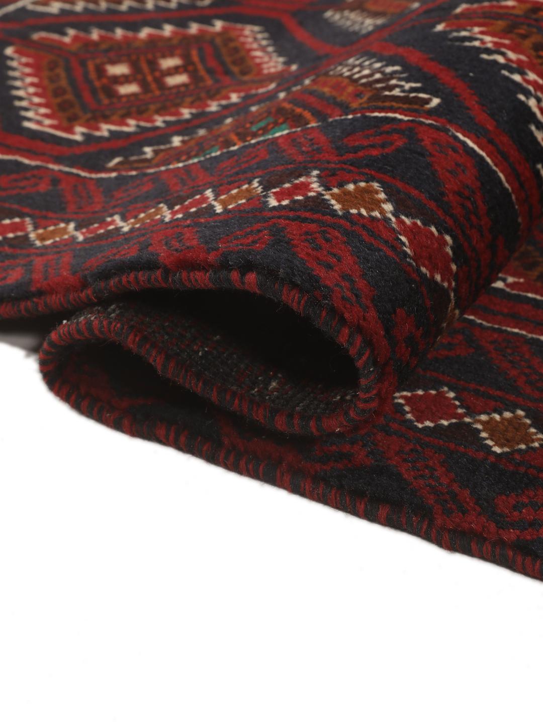 Handgeknoopt Beluch-tapijt uit het Midden-Oosten in donkerrode en donkerblauwe tinten met geometrische motieven.