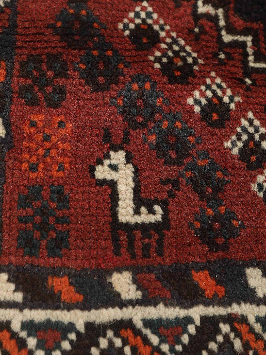 Et håndknyttet Shiraz-tæppe fra Mellemøsten med et mørkerødt og sort geometrisk design.