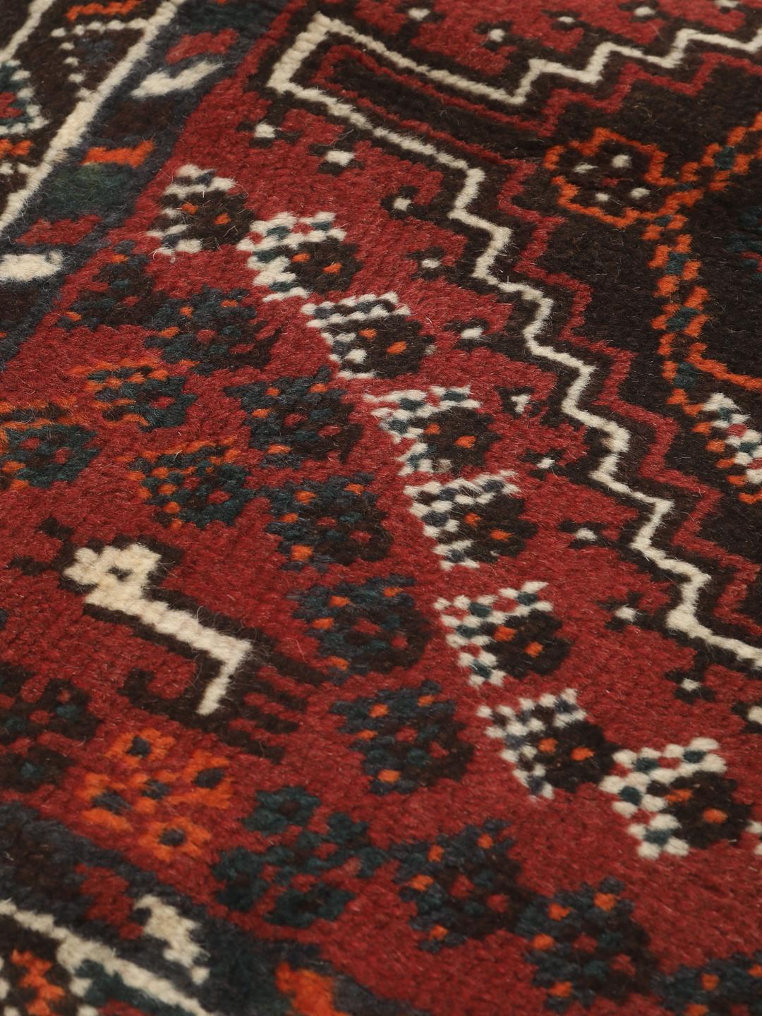 Et håndknyttet Shiraz-tæppe fra Mellemøsten med et mørkerødt og sort geometrisk design.
