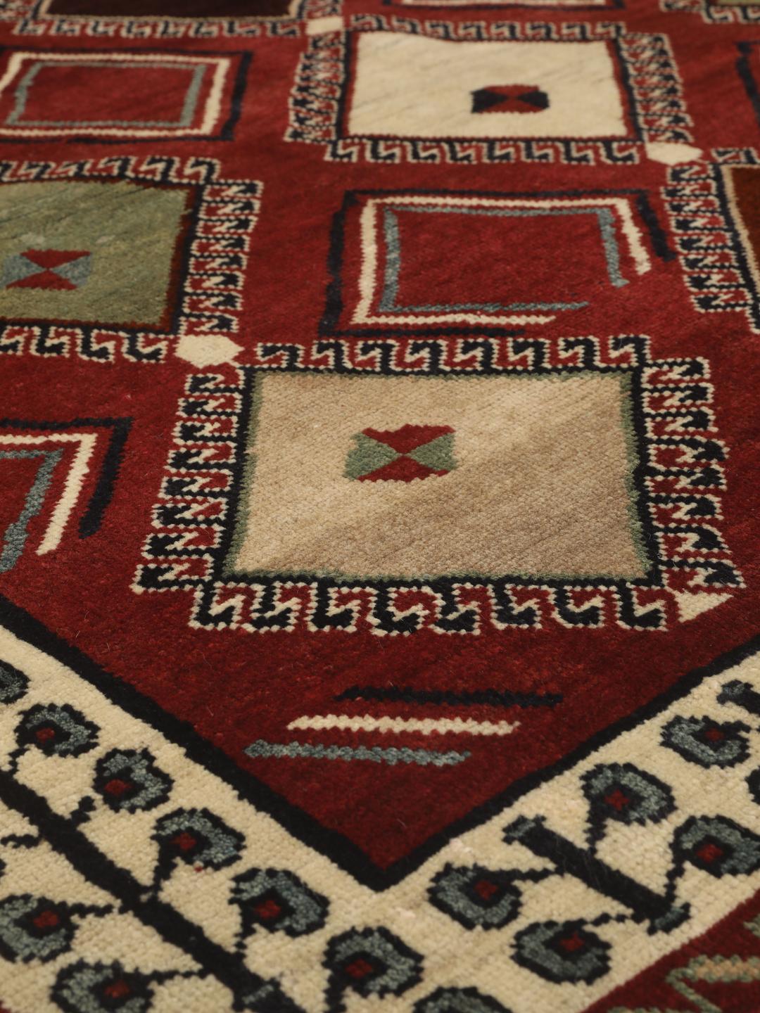 Hand-knotted Ghashghai rug from the Middle East featuring a vibrant red field with geometric diamond motifs.