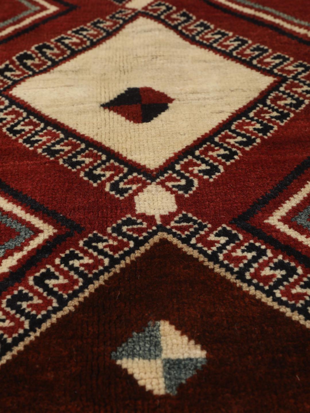 Hand-knotted Ghashghai rug from the Middle East featuring a vibrant red field with geometric diamond motifs.