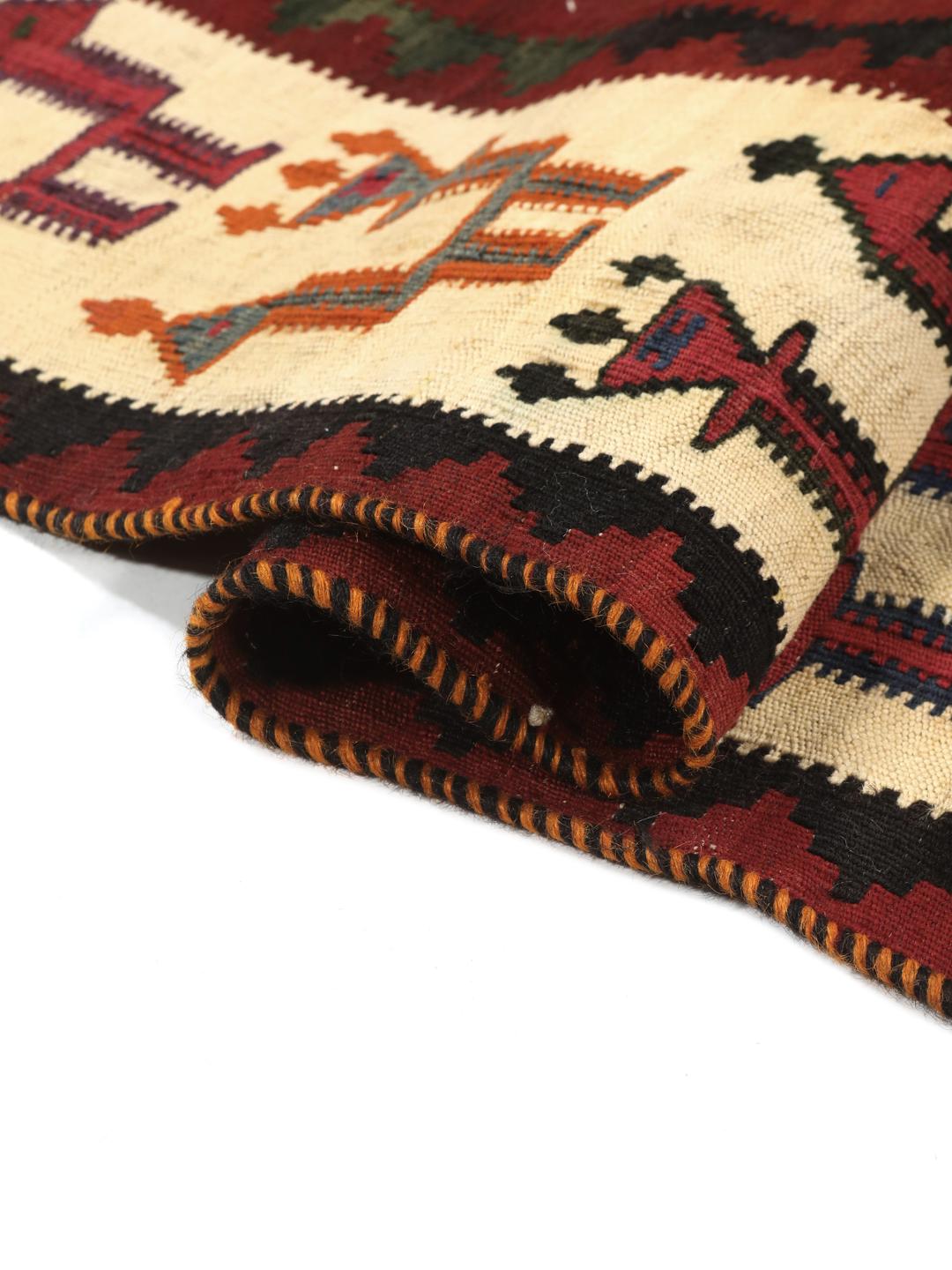 Un tapis kilim vintage tissé à la main provenant du Moyen-Orient, arborant de grands motifs géométriques en forme de losanges dans des tons rouge, vert et crème.