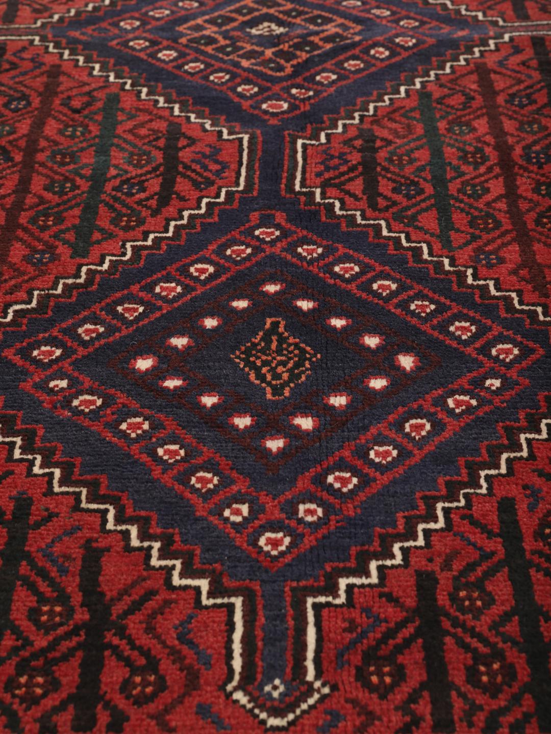 A hand-knotted Shiraz rug from the Middle East in dark-red and dark-blue tones.