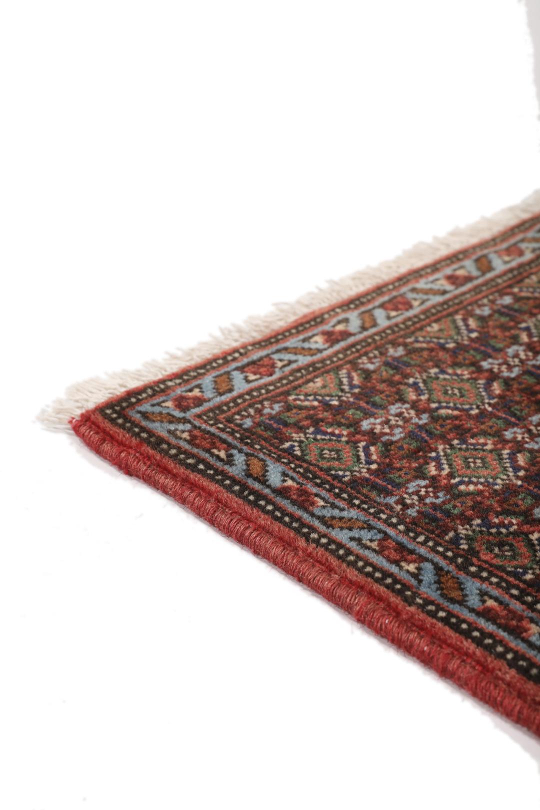 A hand-knotted Senneh rug from the Middle East in dark-red and dark-blue tones.