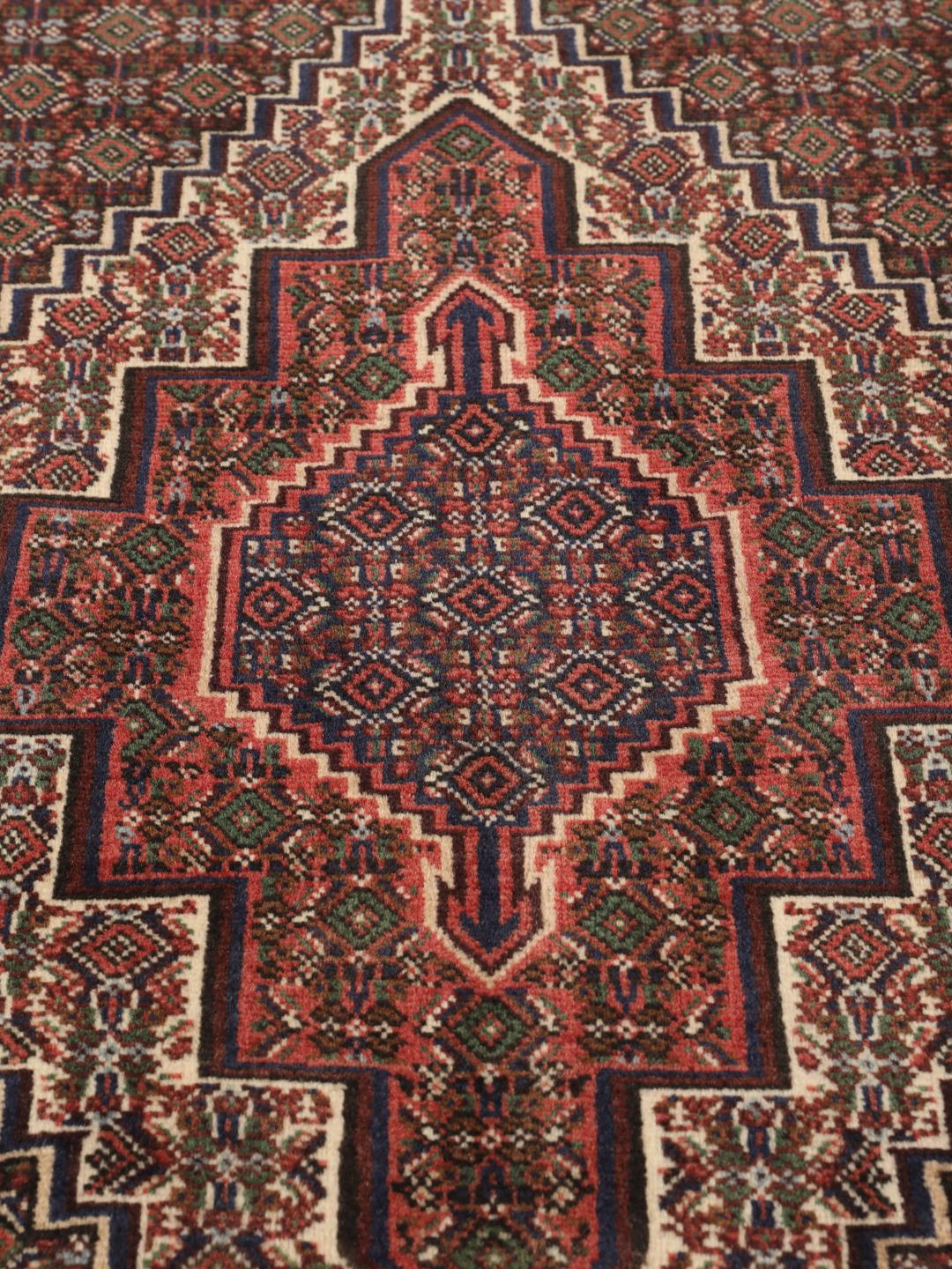 A hand-knotted Senneh rug from the Middle East in dark-red and dark-blue tones.