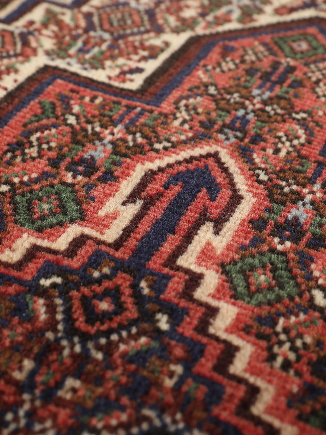 A hand-knotted Senneh rug from the Middle East in dark-red and dark-blue tones.