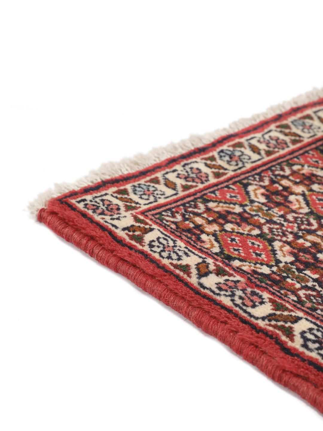 A hand-knotted Senneh rug from the Middle East in red with geometric motifs.