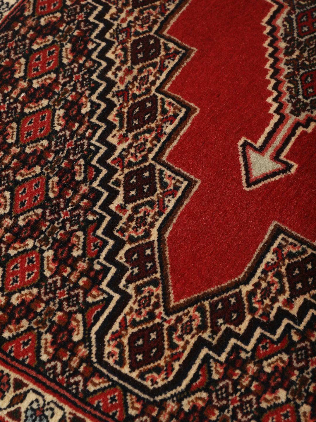 A hand-knotted Senneh rug from the Middle East in red with geometric motifs.