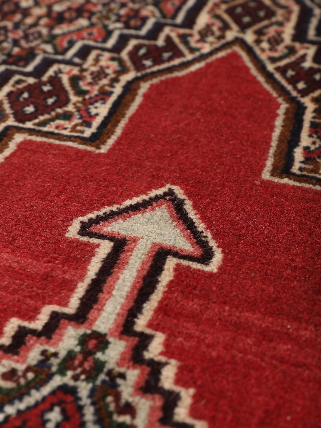 A hand-knotted Senneh rug from the Middle East in red with geometric motifs.