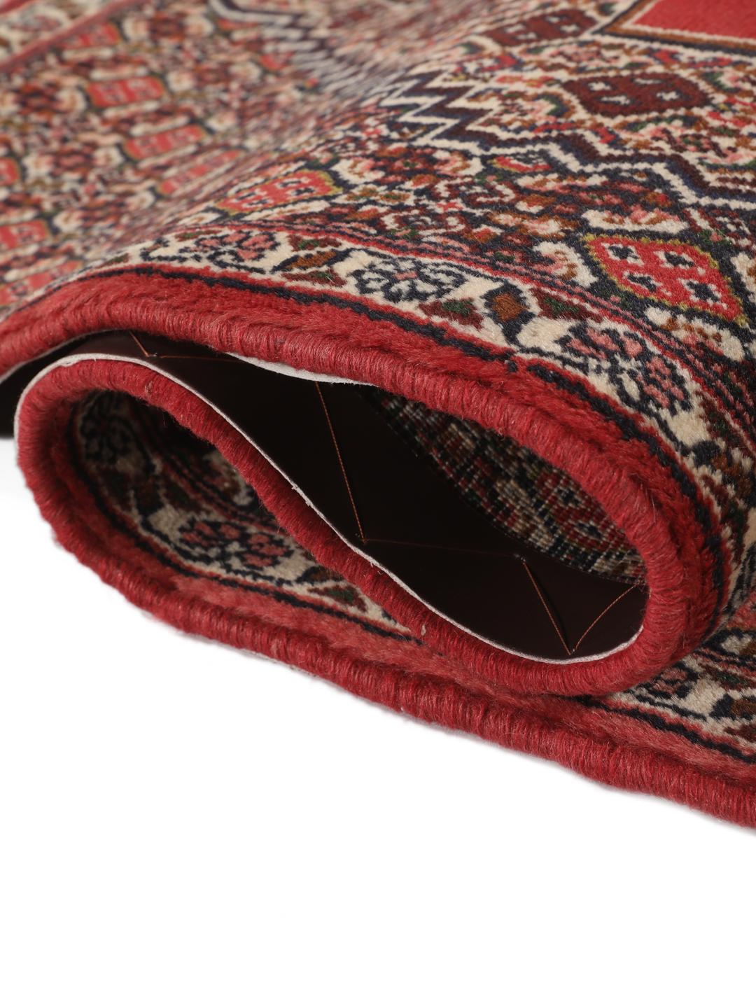 A hand-knotted Senneh rug from the Middle East in red with geometric motifs.