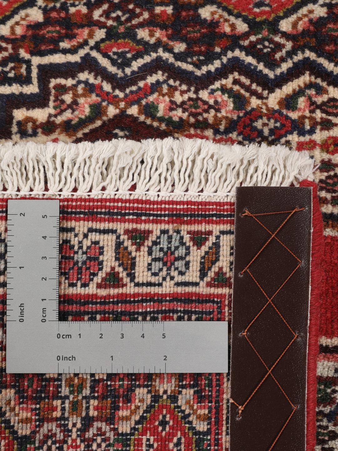 A hand-knotted Senneh rug from the Middle East in red with geometric motifs.