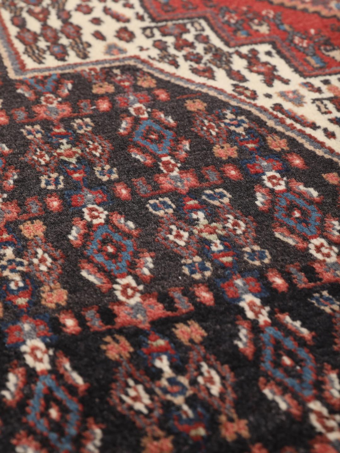 Hand-knotted Senneh rug from the Middle East in dark-blue and dark-red tones.