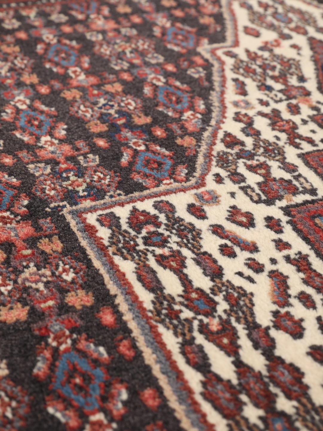 Hand-knotted Senneh rug from the Middle East in dark-blue and dark-red tones.