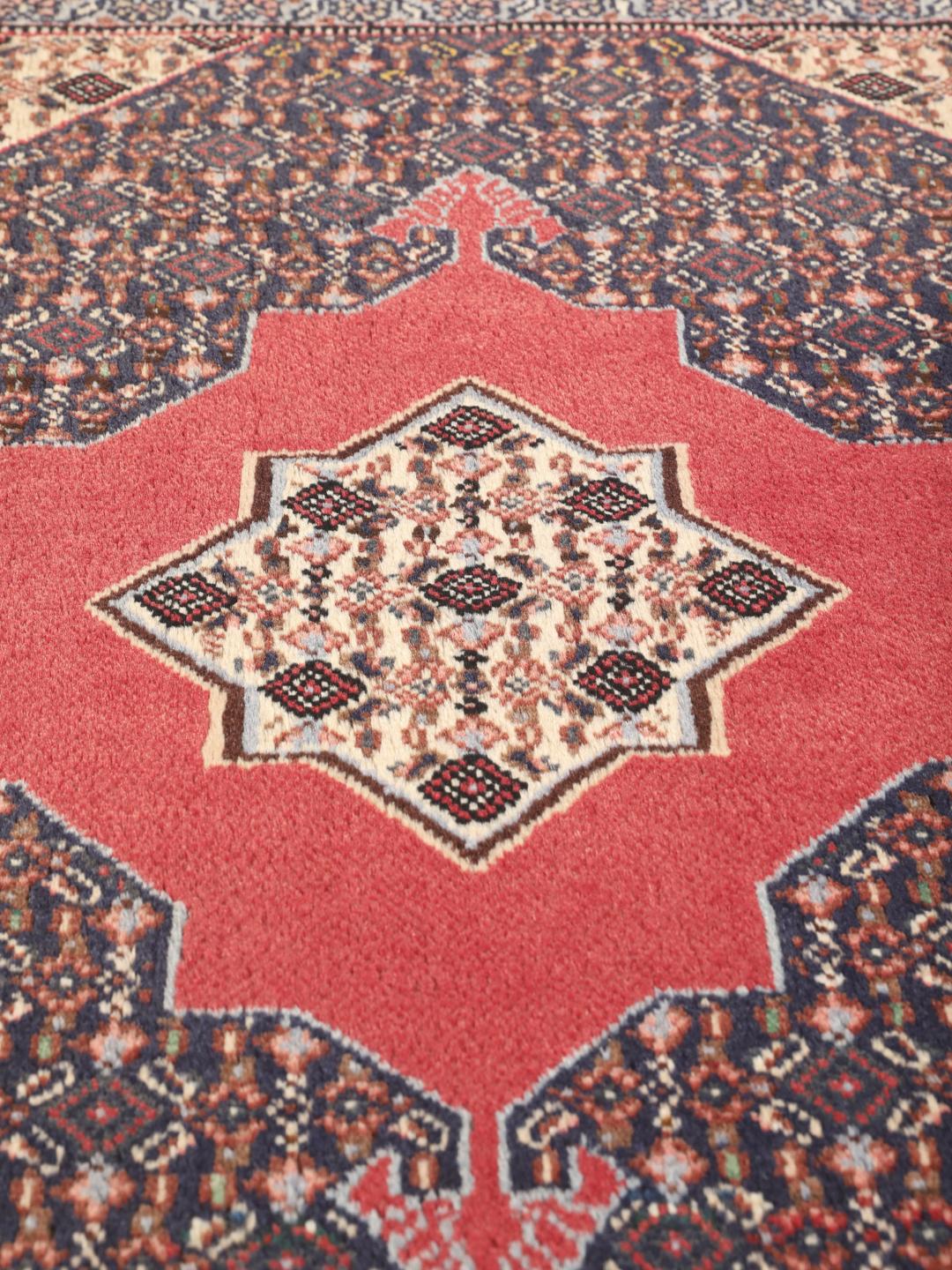 Ein handgeknüpfter Senneh-Teppich aus dem Nahen Osten mit einem roten und blauen geometrischen Design.