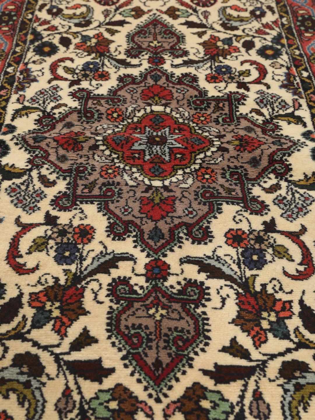 Een met de hand geknoopte Asadabad loper met een bloemmotief in beige, rode en blauwe tinten.