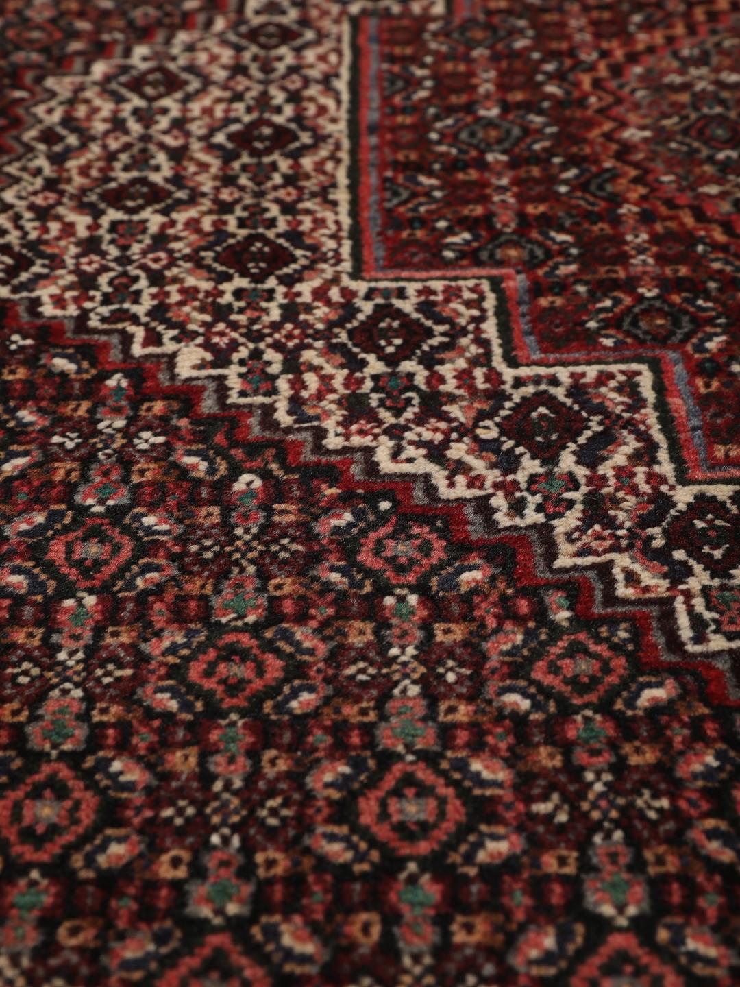 Hand-knotted Senneh rug from the Middle East in dark-red and black tones.