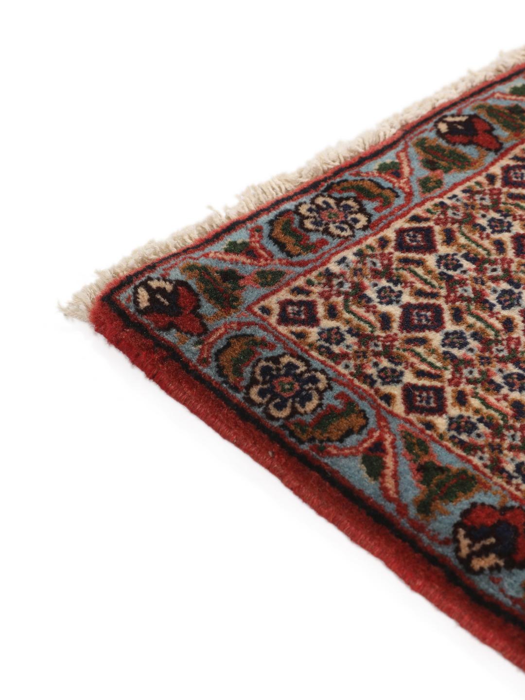 A hand-knotted Senneh rug from the Middle East featuring a red and dark-blue patterned design.