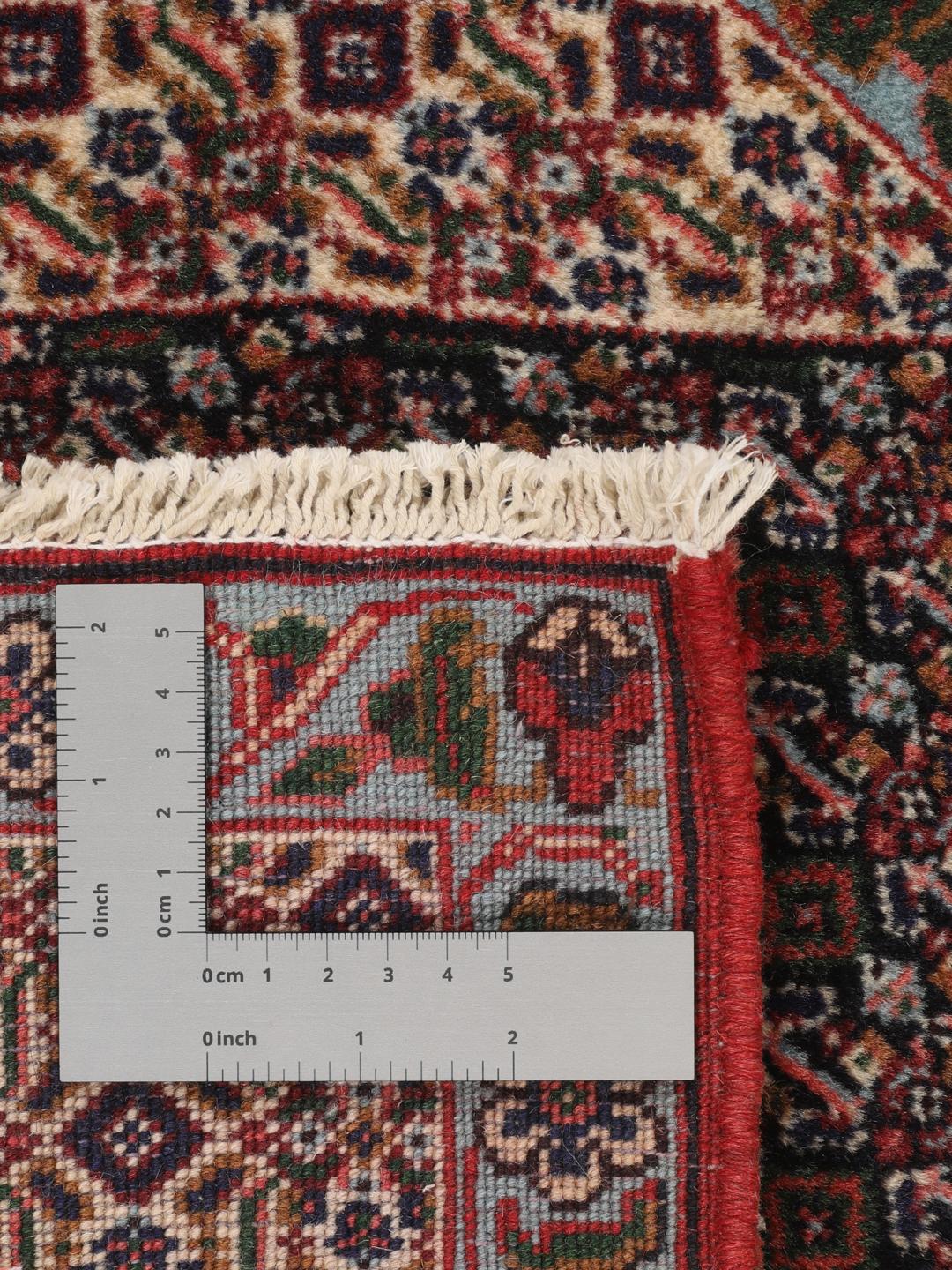 A hand-knotted Senneh rug from the Middle East featuring a red and dark-blue patterned design.