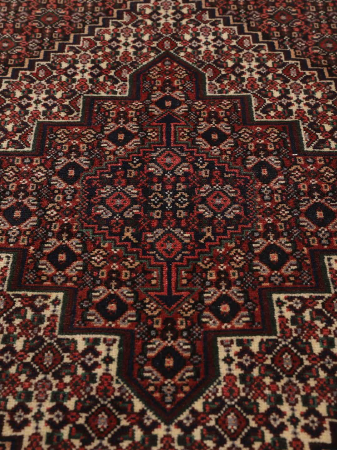 Ein handgeknüpfter Senneh-Teppich mit einem dunkelroten und schwarzen geometrischen Muster.