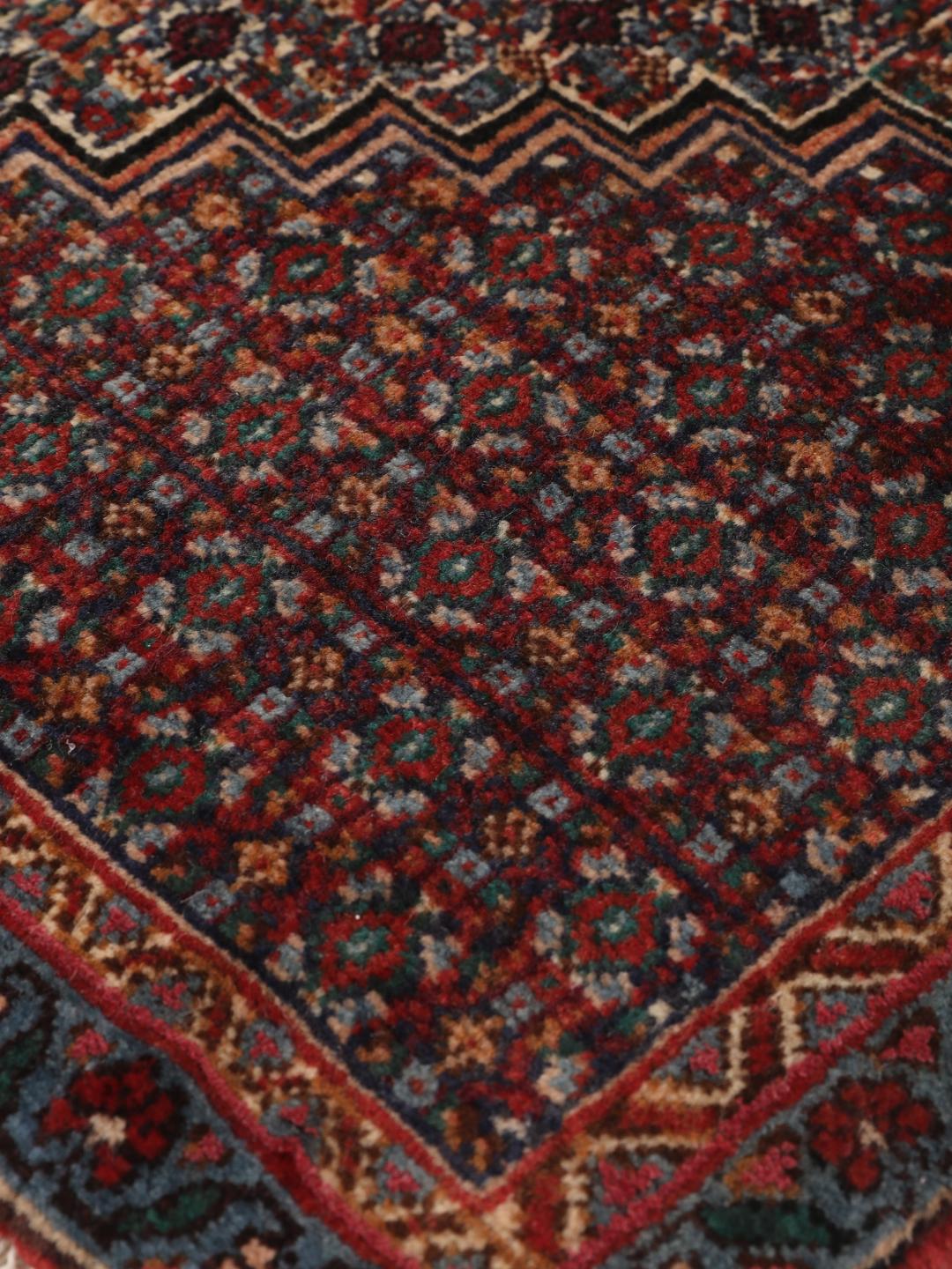 Ein handgeknüpfter Senneh Wolle-Teppich aus dem Mittleren Osten mit einem dunkelroten und blauen Medaillon-Muster.
