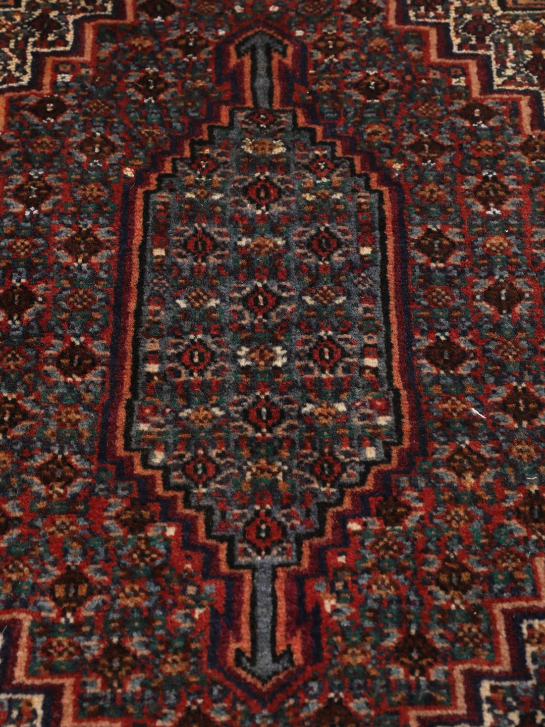 Ein handgeknüpfter Senneh Wolle-Teppich aus dem Mittleren Osten mit einem dunkelroten und blauen Medaillon-Muster.