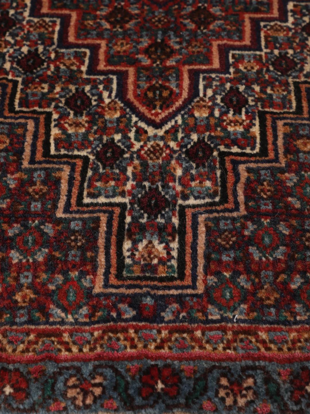 Ein handgeknüpfter Senneh Wolle-Teppich aus dem Mittleren Osten mit einem dunkelroten und blauen Medaillon-Muster.