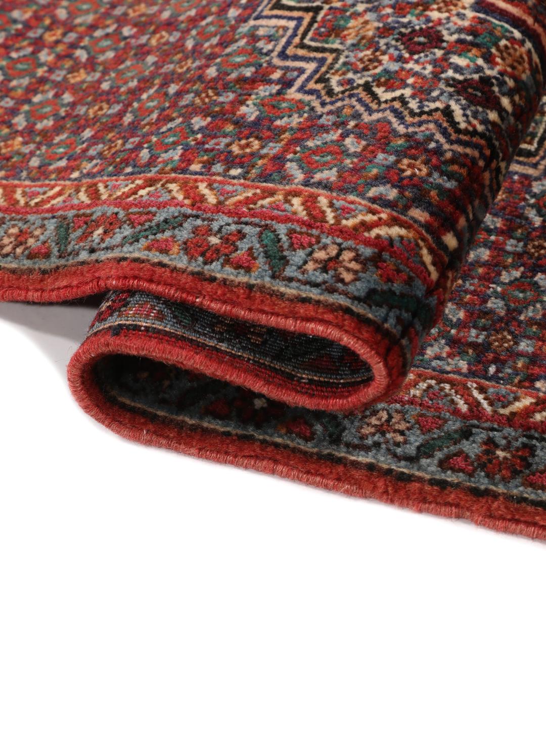 Ein handgeknüpfter Senneh Wolle-Teppich aus dem Mittleren Osten mit einem dunkelroten und blauen Medaillon-Muster.