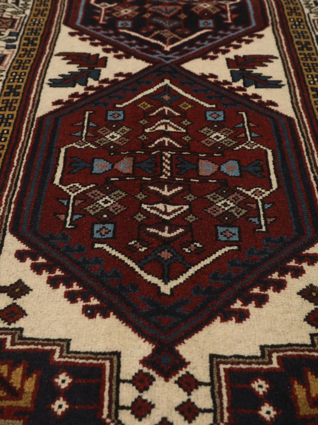 Een handgeknoopte Ardebil loper met donkerrode en beige geometrische patronen uit het Midden-Oosten.