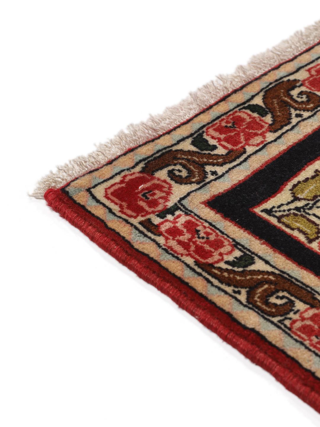 Een handgeknoopt Senneh-tapijt uit het Midden-Oosten met een rood veld en decoratieve bloemenranden.