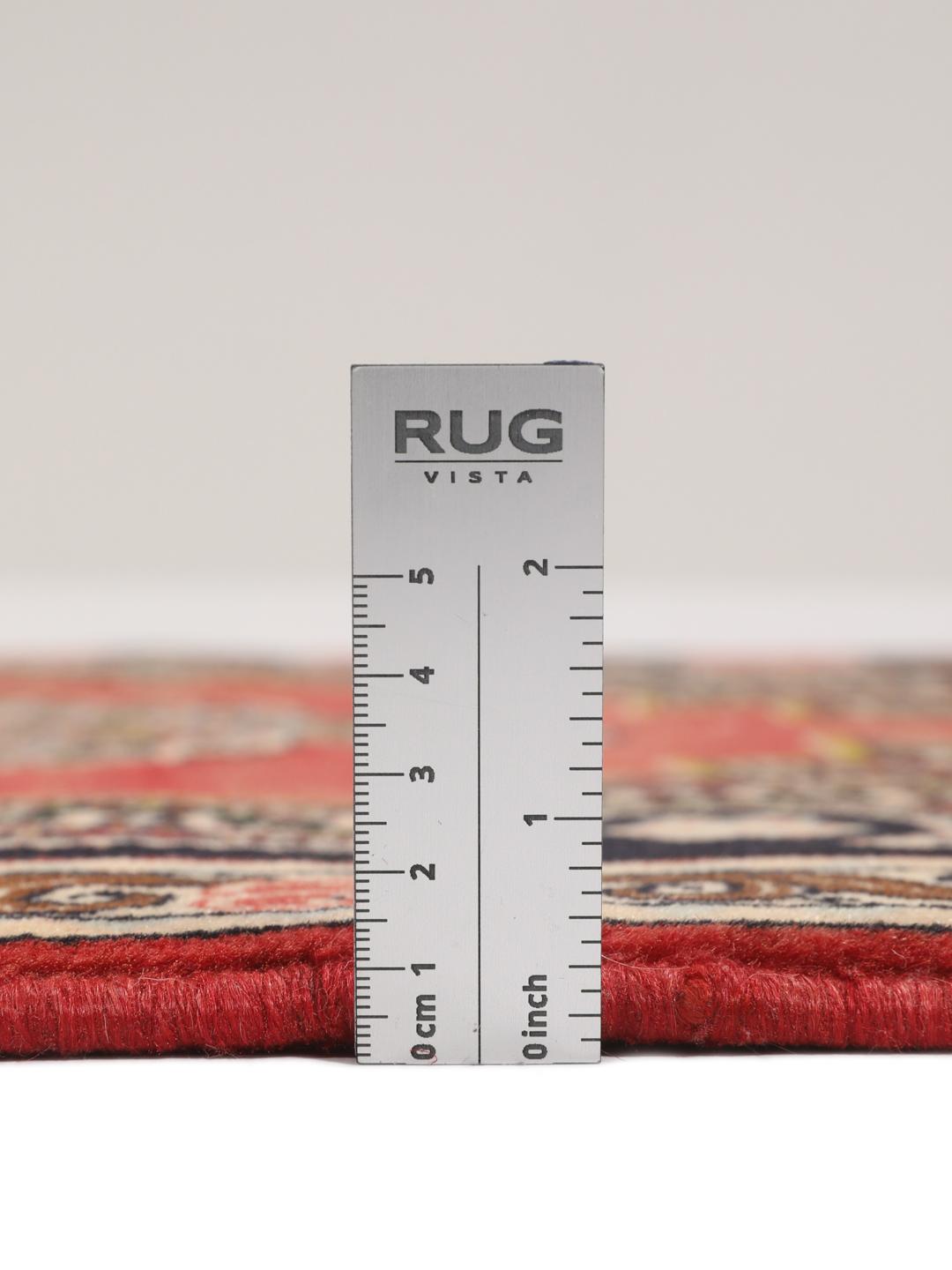 Een handgeknoopt Senneh-tapijt uit het Midden-Oosten met een rood veld en decoratieve bloemenranden.