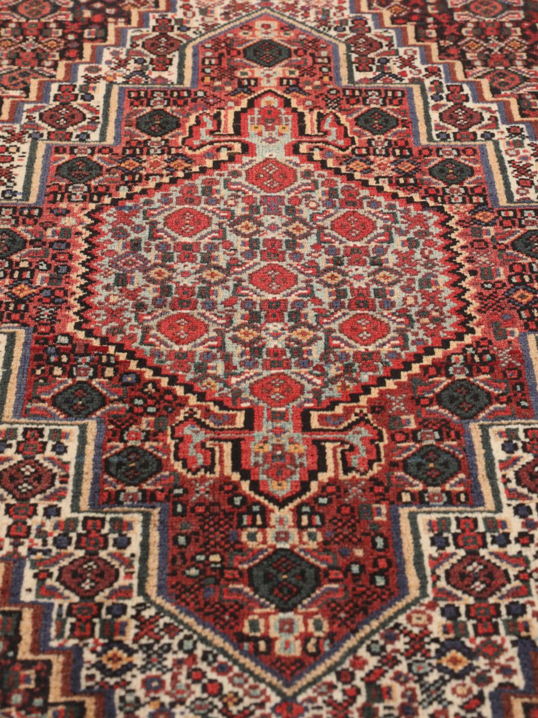 A hand-knotted Senneh rug from the Middle East in dark-red and dark-blue tones.