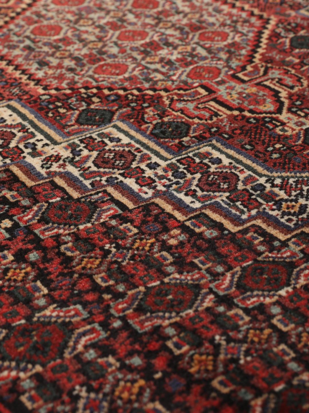 A hand-knotted Senneh rug from the Middle East in dark-red and dark-blue tones.