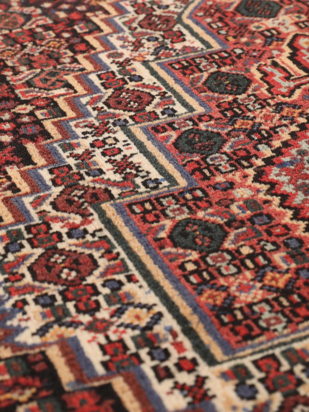 A hand-knotted Senneh rug from the Middle East in dark-red and dark-blue tones.