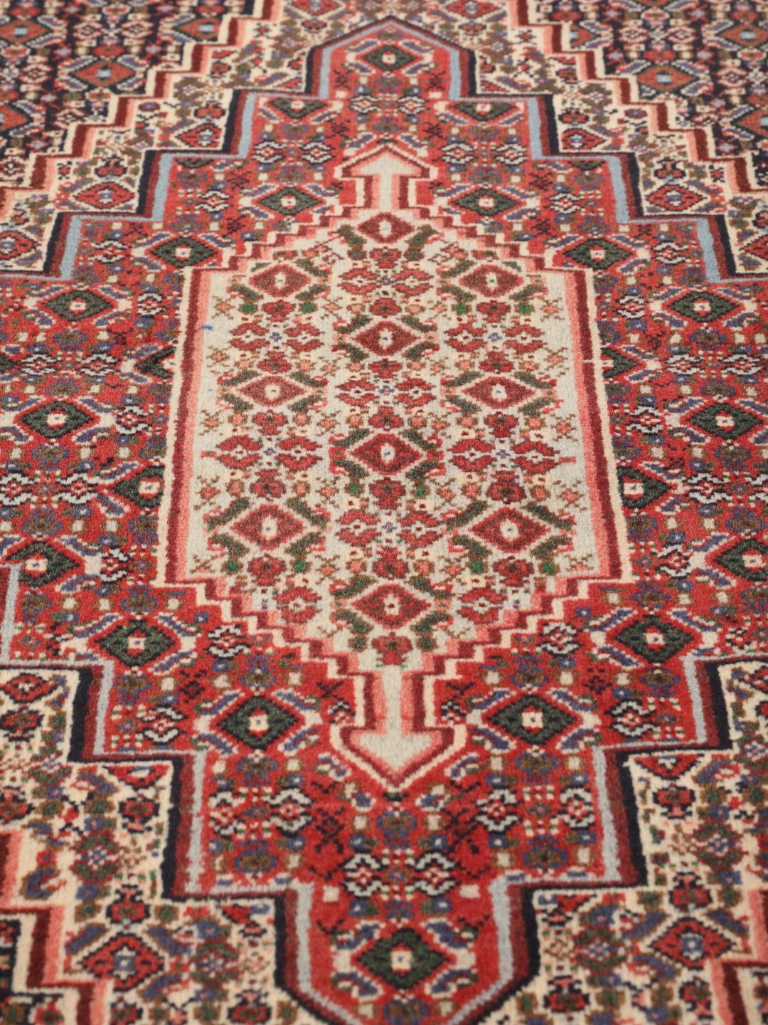 Hand-knotted Senneh wool rug in red with intricate geometric medallion patterns