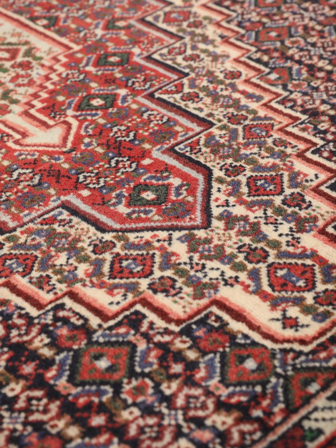 Hand-knotted Senneh wool rug in red with intricate geometric medallion patterns