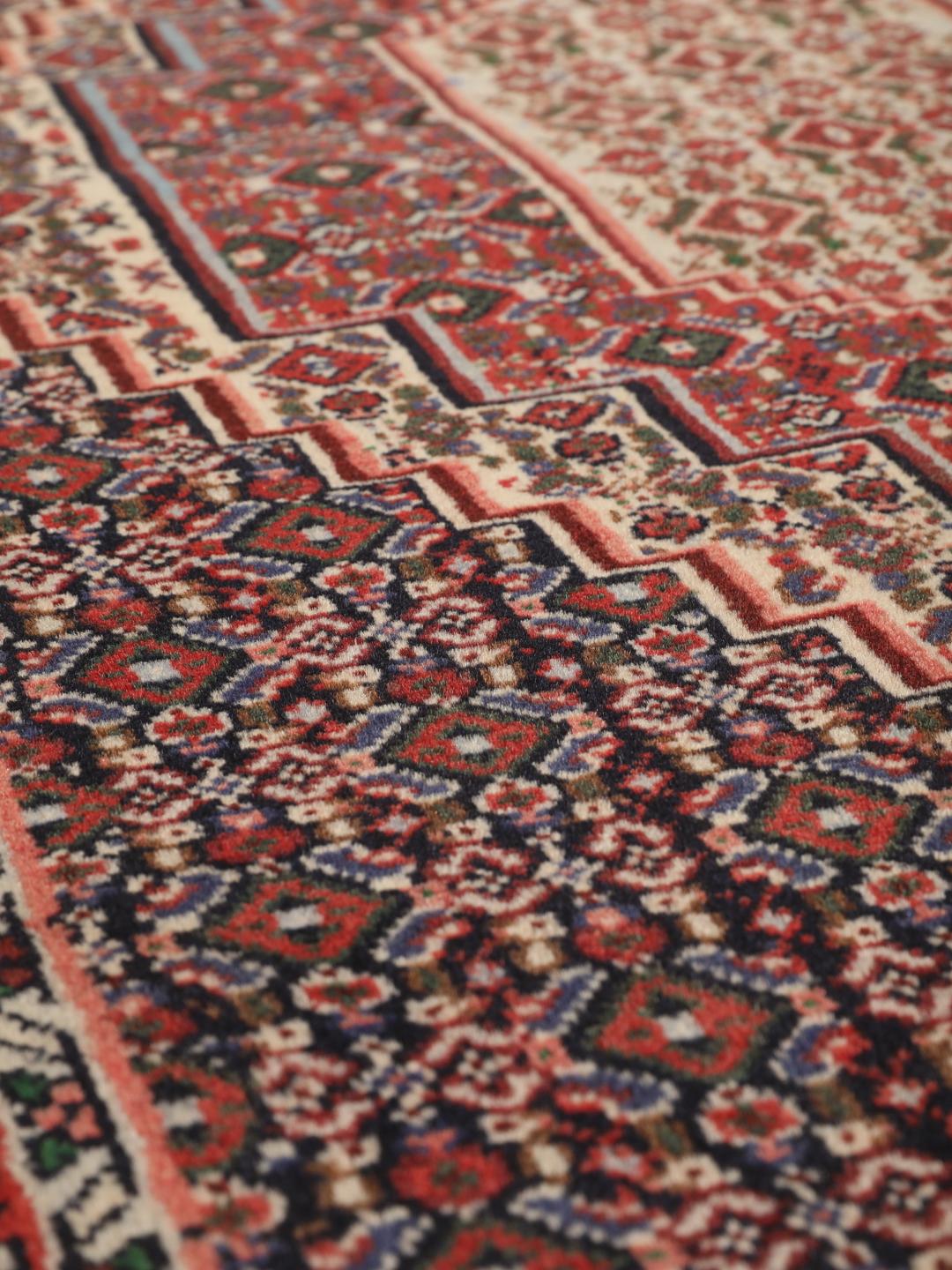 Hand-knotted Senneh wool rug in red with intricate geometric medallion patterns