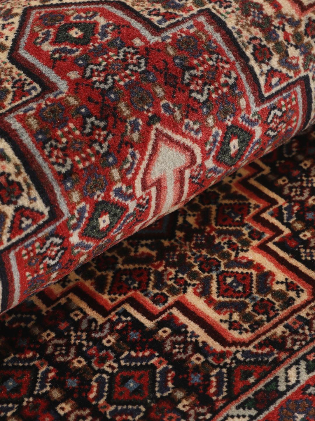 Hand-knotted Senneh wool rug in red with intricate geometric medallion patterns
