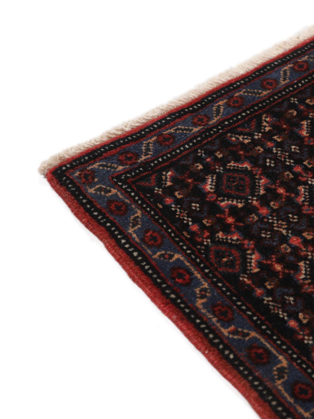 A hand-knotted Senneh rug from the Middle East in dark-blue and dark-red tones.