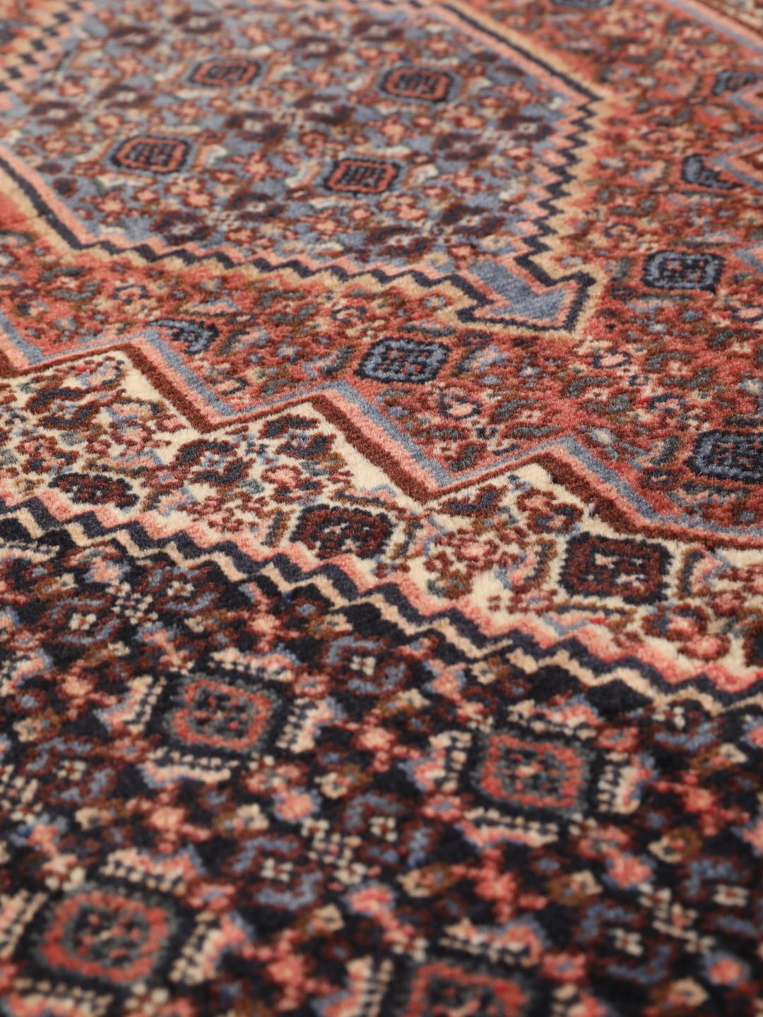 A hand-knotted Senneh rug from the Middle East in dark-blue and dark-red tones.